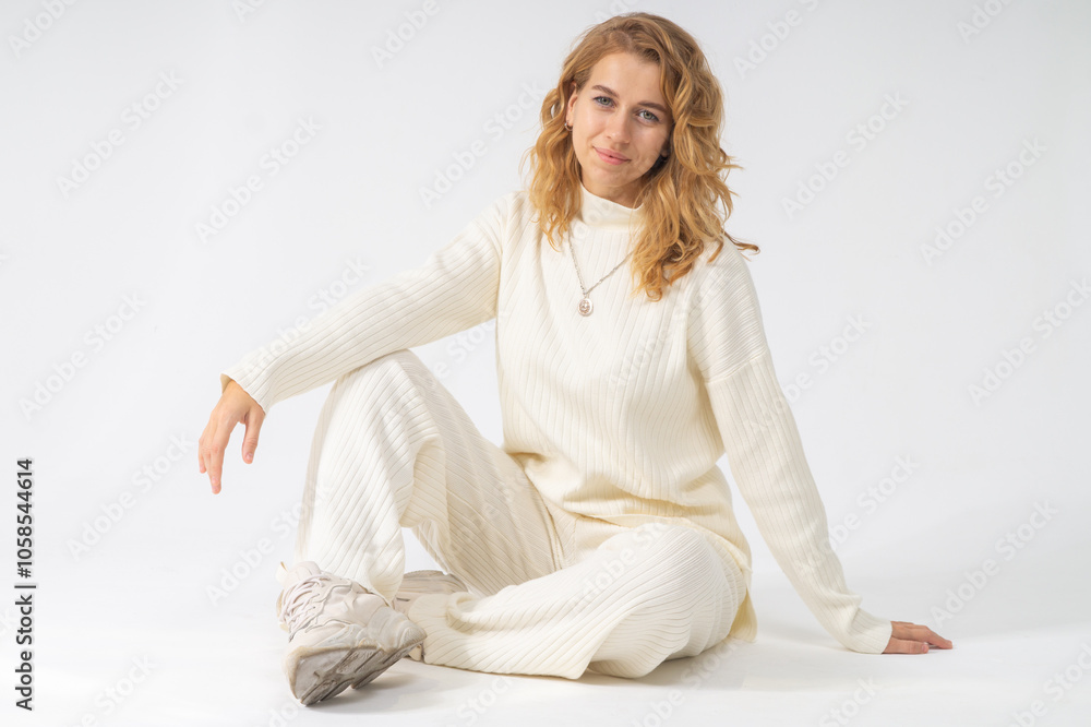 Cute young blonde girl sitting on a floor, white background, copy space Cute young blonde girl sitting on a floor, white background, copy space