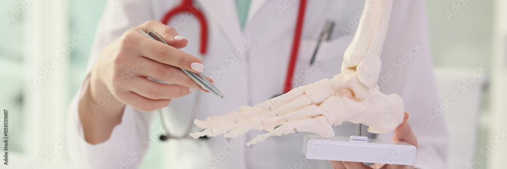Therapist doctor shows foot skeleton to patient in clinic