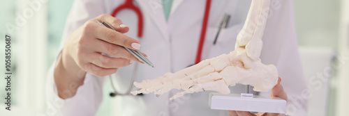 Obraz na płótnie Therapist doctor shows foot skeleton to patient in clinic w salonie