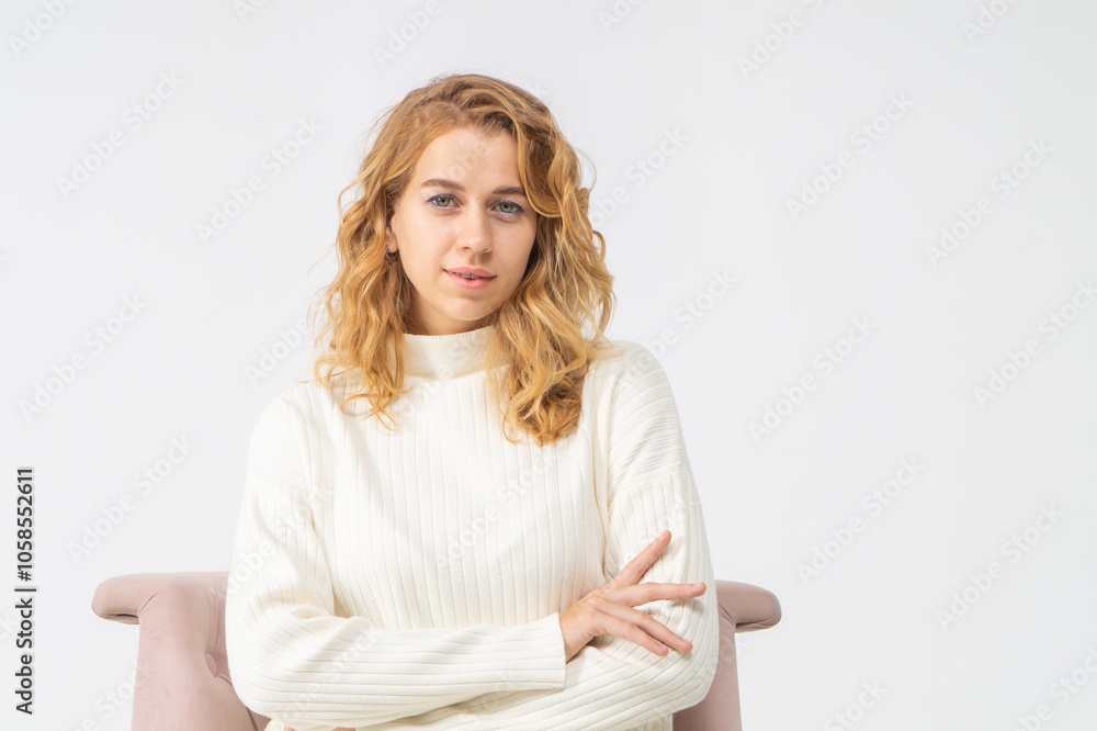 Attractive young blonde girl sits in a pink chair, white background, copy space Attractive young blonde girl sits in a pink chair, white background, copy space