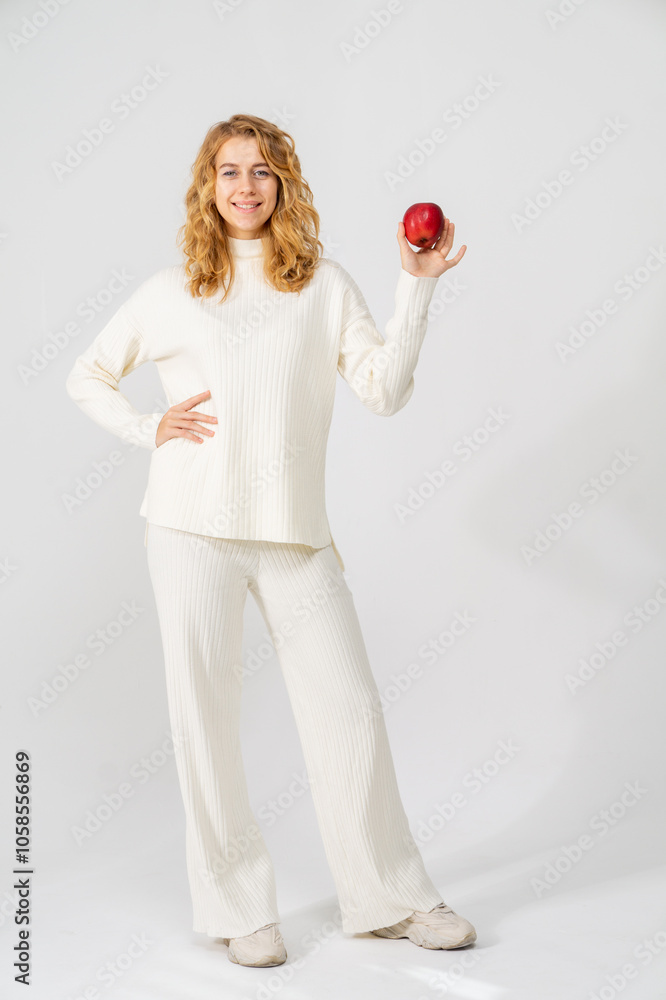 Happy attractive blonde young girl holding a red apple, white background, copyspace, full-length portrait Happy attractive blonde young girl holding a red apple, white background, copyspace, full-length portrait