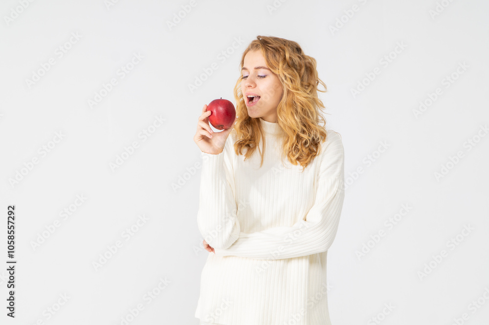 Happy attractive blonde young girl holding a red apple, white background, copyspace, bust portrait Happy attractive blonde young girl holding a red apple, white background, copyspace, bust portrait
