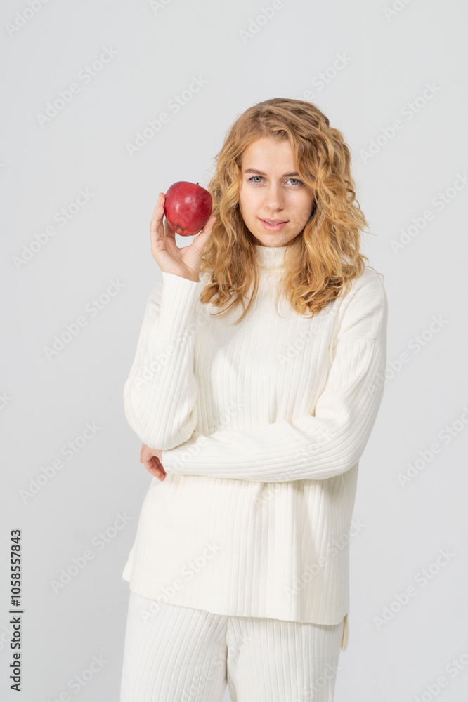 Happy attractive blonde young girl holding a red apple, white background, copyspace, bust portrait Happy attractive blonde young girl holding a red apple, white background, copyspace, bust portrait