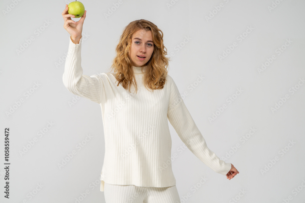 Happy attractive blonde young girl holding a green apple, white background, copyspace Happy attractive blonde young girl holding a green apple, white background, copyspace
