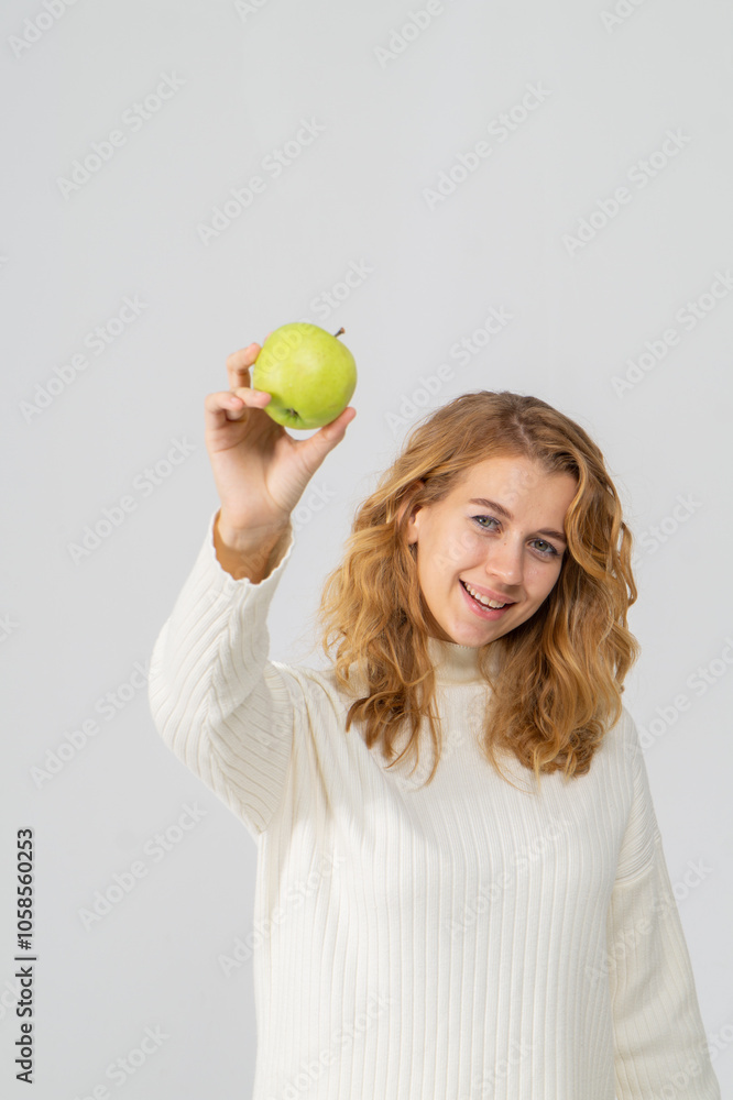 Happy attractive blonde young girl holding a green apple, white background, copyspace Happy attractive blonde young girl holding a green apple, white background, copyspace