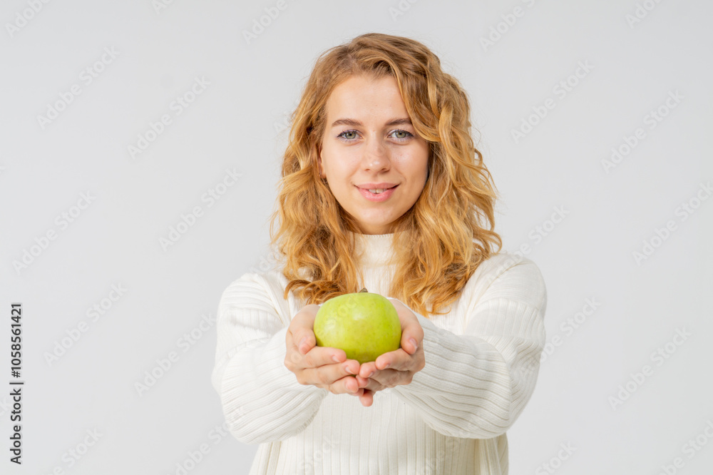 Happy attractive blonde young girl holding a green apple, white background, copyspace Happy attractive blonde young girl holding a green apple, white background, copyspace
