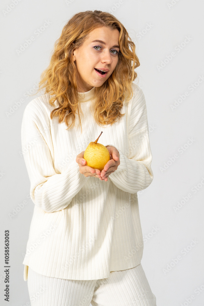Happy attractive blonde young girl holding a yellow pear, white background, copyspace Happy attractive blonde young girl holding a yellow pear, white background, copyspace