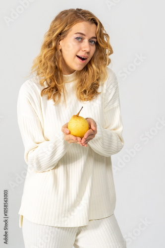 Wallpaper Mural Happy attractive blonde young girl holding a yellow pear, white background, copyspace Torontodigital.ca