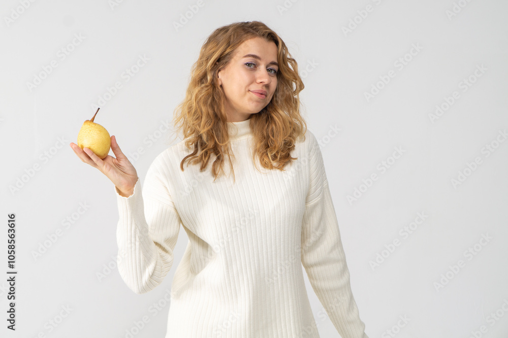 Happy attractive blonde young girl holding a yellow pear, white background, copyspace Happy attractive blonde young girl holding a yellow pear, white background, copyspace