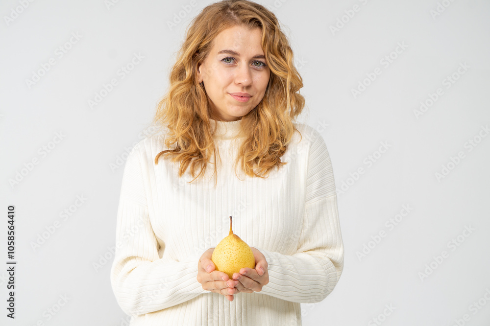 Happy attractive blonde young girl holding a yellow pear, white background, copyspace Happy attractive blonde young girl holding a yellow pear, white background, copyspace