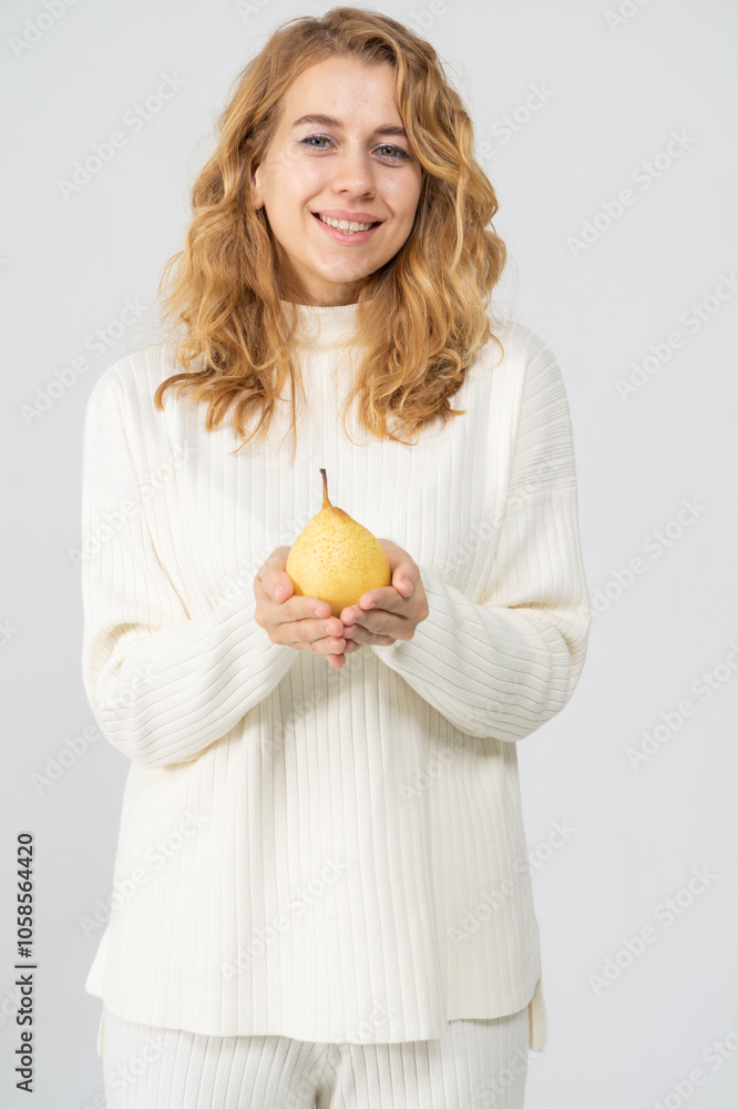 Happy attractive blonde young girl holding a yellow pear, white background, copyspace Happy attractive blonde young girl holding a yellow pear, white background, copyspace