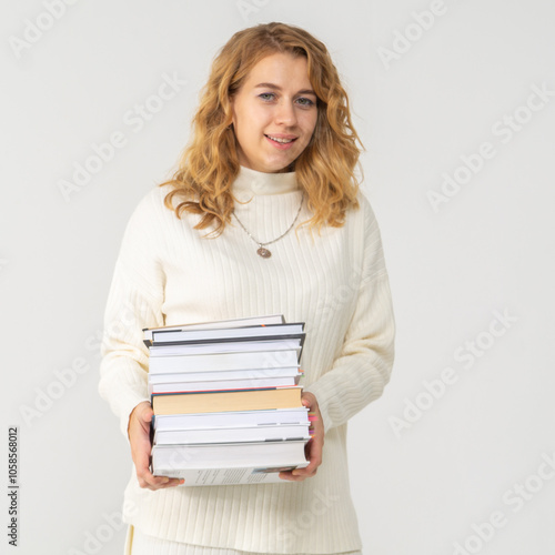 Cute young blonde girl with books in her hands, white background, copyspace