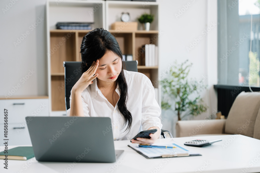 Asian business woman is stressed, bored, and overthinking from working on a tablet Asian business woman is stressed, bored, and overthinking from working on a tablet