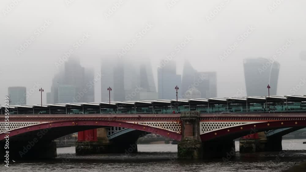 View of the Blackfriars Bridge on the river thames with iconic London financial district skyscrapers in the background during a rainy misty day. View of the Blackfriars Bridge on the river thames with iconic London financial district skyscrapers in the background during a rainy misty day.