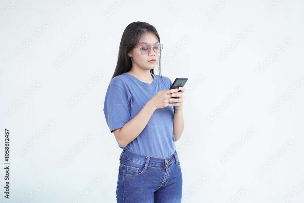 beautiful Asian woman with a serious expression exchanges messages on her smartphone against a white background beautiful Asian woman with a serious expression exchanges messages on her smartphone against a white background