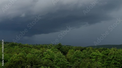 Fly over a summer wilderness forests towards a thunder and lighting storm. Room for text, drone footage