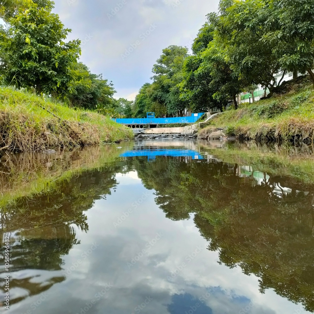 a river flowing through a lush green landscape. The calm water reflects the surrounding trees and the sky, creating a mirror-like effect. a river flowing through a lush green landscape. The calm water reflects the surrounding trees and the sky, creating a mirror-like effect.