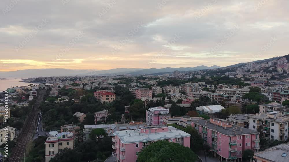 Genoa’s colorful buildings at sunset with a train track running through the city, aerial view Genoa’s colorful buildings at sunset with a train track running through the city, aerial view