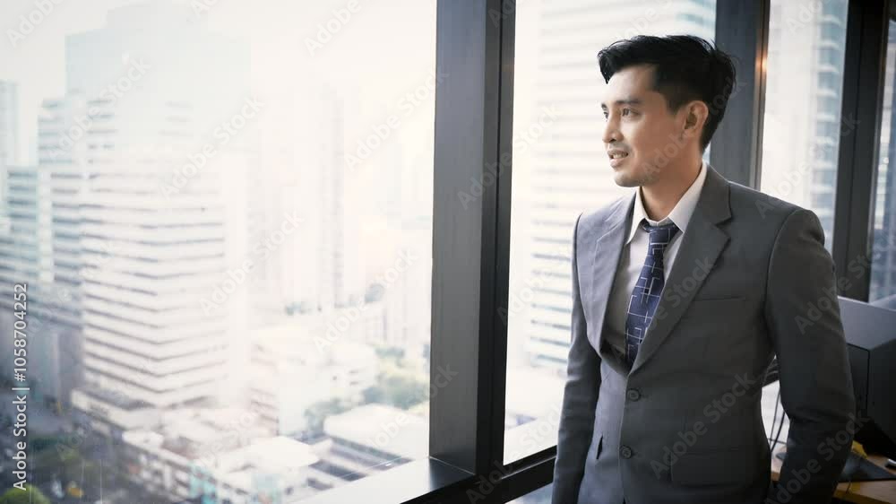 Business man standing and looking out of windows at office Business man standing and looking out of windows at office
