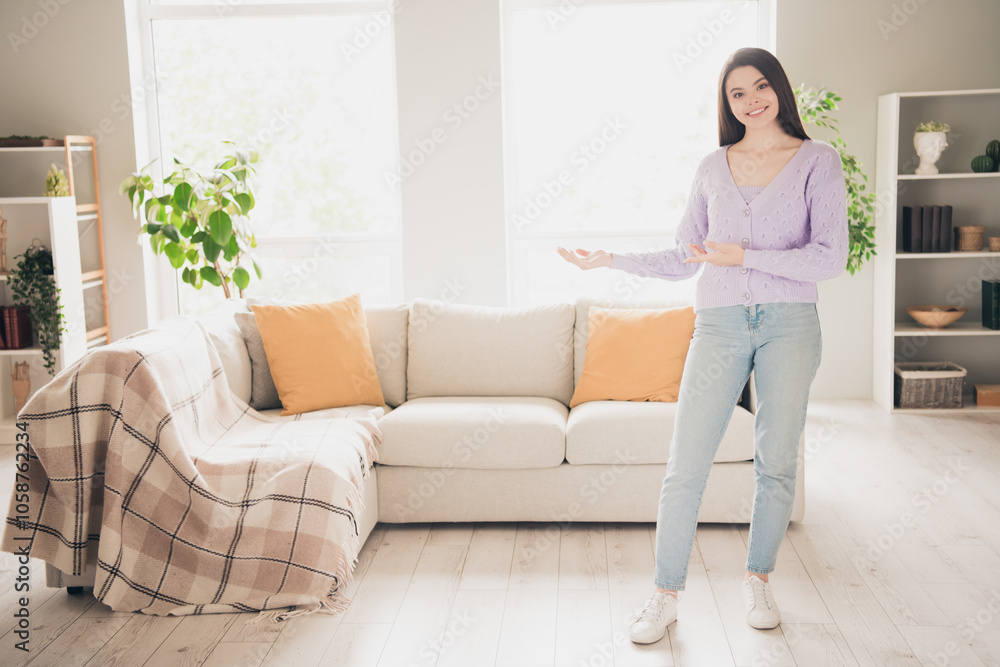 Full length photo of lovely young teen girl hands point welcome dressed violet garment spacious house bright indoors room Full length photo of lovely young teen girl hands point welcome dressed violet garment spacious house bright indoors room