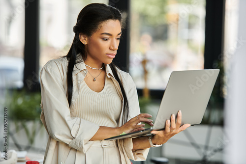 A focused woman engages with her laptop, immersed in work at a stylish office space.