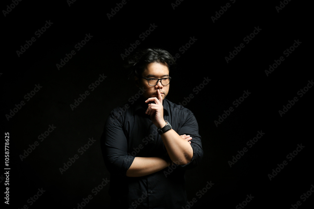 Low key portrait of a man. Asian man in black shirt over black background Low key portrait of a man. Asian man in black shirt over black background