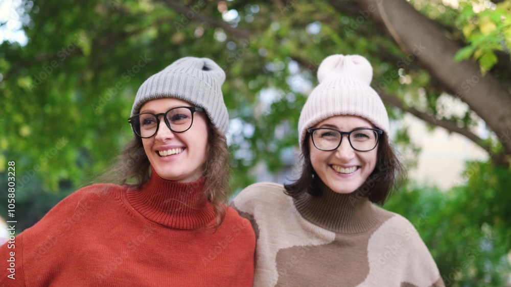 Fototapeta premium Two girlfriends are walking and having fun outside among autumn trees in a city park.
