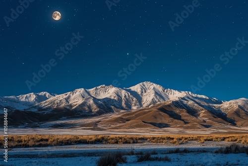 Montagnes enneigées sous ciel étoilé et pleine lune au-dessus des plaines.. photo