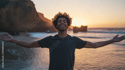 A young man spreads his arms joyfully on a beach during sunset, embracing freedom and happiness. His silhouette against the scenic shore captures the moment’s beauty.
