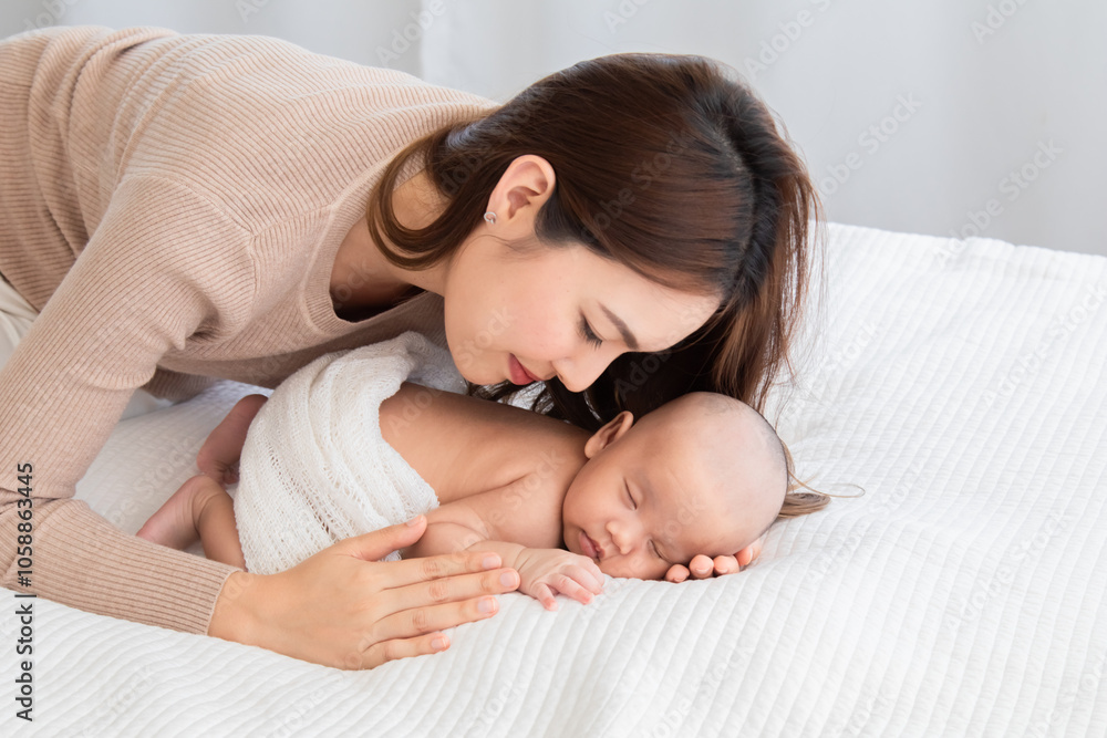 Selective focus of newborn baby deep sleeping on white bed. Asian beautiful mother hugging, cuddling and gently holding adorable infant hand with soft and care. Child healthcare sleep in mom's hand Selective focus of newborn baby deep sleeping on white bed. Asian beautiful mother hugging, cuddling and gently holding adorable infant hand with soft and care. Child healthcare sleep in mom's hand