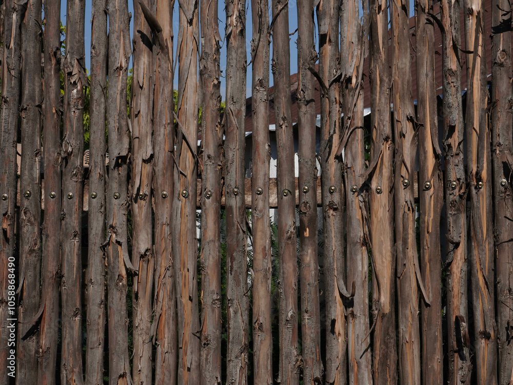 A wooden handmade fence from natural logs in a public park. A wooden handmade fence from natural logs in a public park.
