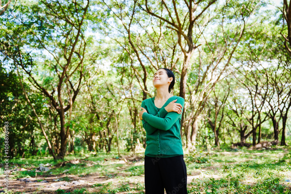 Young Asian woman sits under a shady tree in a park, enjoying her free time in nature. She breathes deeply, refreshing herself, surrounded by leaves and the tranquility of greenery. Young Asian woman sits under a shady tree in a park, enjoying her free time in nature. She breathes deeply, refreshing herself, surrounded by leaves and the tranquility of greenery.