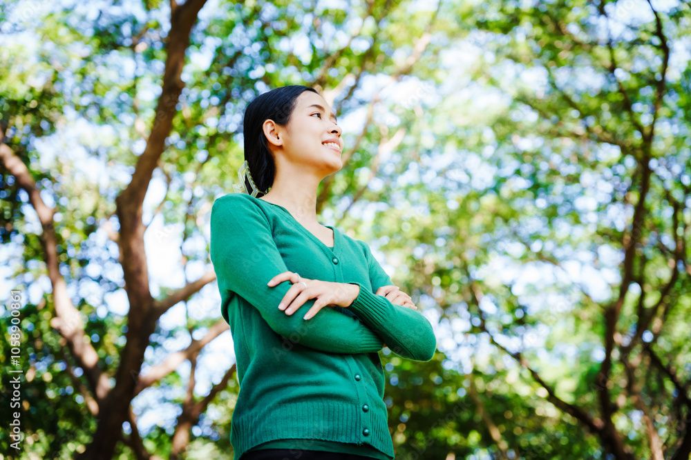 Young Asian woman sits under a shady tree in a park, enjoying her free time in nature. She breathes deeply, refreshing herself, surrounded by leaves and the tranquility of greenery. Young Asian woman sits under a shady tree in a park, enjoying her free time in nature. She breathes deeply, refreshing herself, surrounded by leaves and the tranquility of greenery.