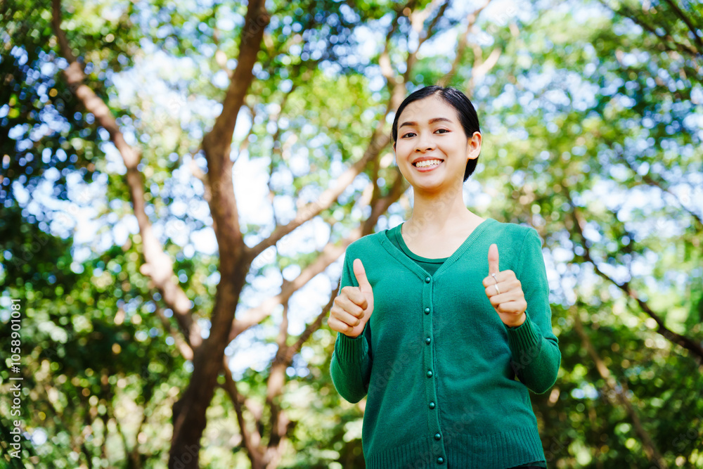Young Asian woman sits under a shady tree in a park, enjoying her free time in nature. She breathes deeply, refreshing herself, surrounded by leaves and the tranquility of greenery. Young Asian woman sits under a shady tree in a park, enjoying her free time in nature. She breathes deeply, refreshing herself, surrounded by leaves and the tranquility of greenery.