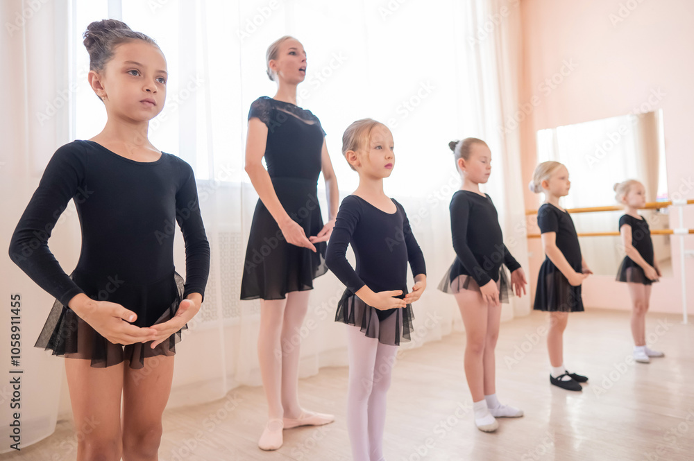 Naklejka premium Children's ballet school. Caucasian woman teaching ballet to little girls.