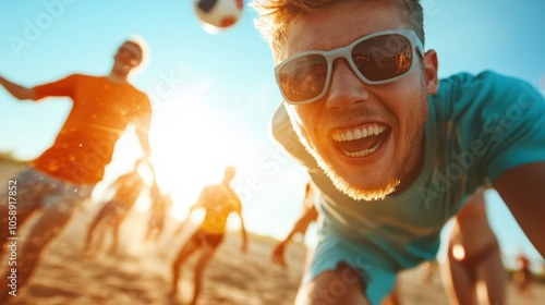 A young man in sunglasses plays beach soccer, captured in motion with his friends under the bright sun, radiating joy and high-spirited energy in this scene.