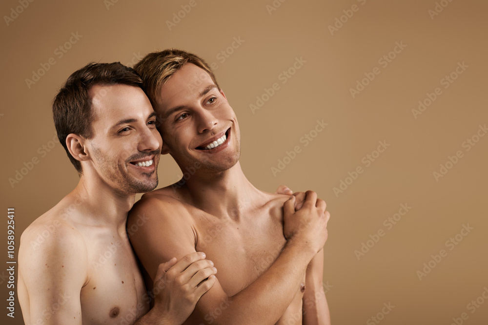 Two young men embrace closely, smiling warmly in a cozy, neutral toned environment. Two young men embrace closely, smiling warmly in a cozy, neutral toned environment.