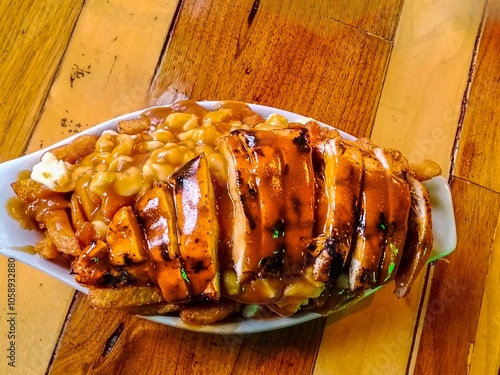 Poutine Dish with grilled chicken in a oval plate on a wooden table at an Old Montreal Restaurant in Quebec Province, Cheese French fries and sauce