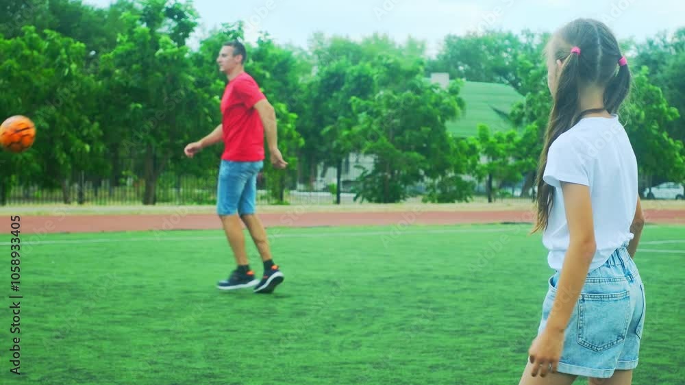 Father and daughter having fun playing soccer. Family dribbling ball together outdoors. Joyful playtime on grass in sport field, stadium. Active bonding time outside. Soccer game with ball for family 