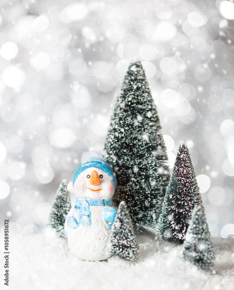 Toy Snowman on snow among fir trees with snowfall. Holiday greeting card template for Christmas or New Year