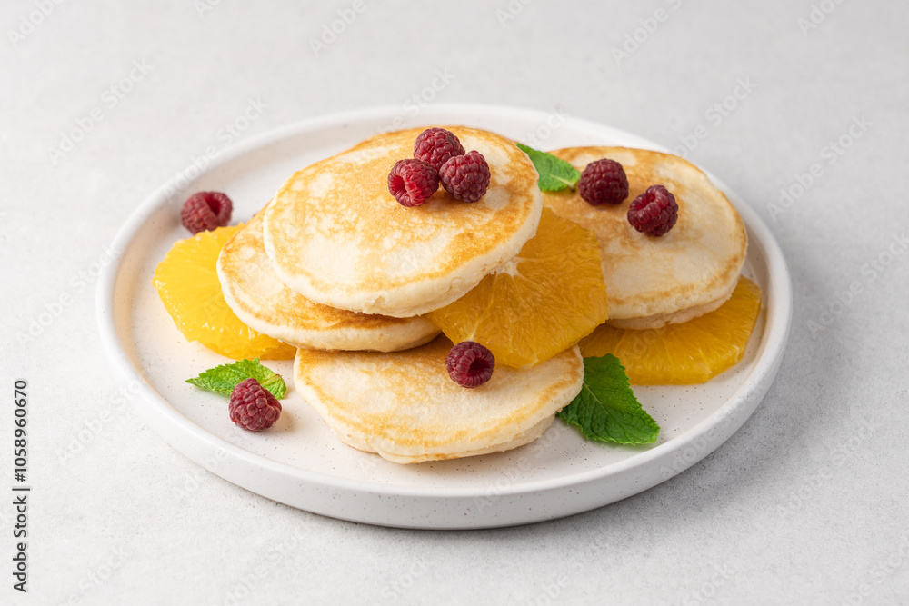 Pancakes with orange and raspberries in plate top view on white background with copy space Pancakes with orange and raspberries in plate top view on white background with copy space