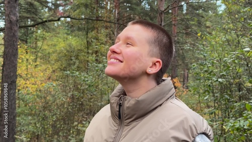 beautiful young woman with short hair in the forest walking and enjoying the weather, breathing fresh air photo