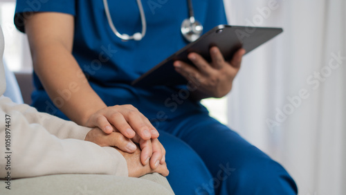 A caring female nurse holds hands to encourage and comfort a retired woman. A carer who helps an elderly woman give medical advice and records information for a retired elderly woman.