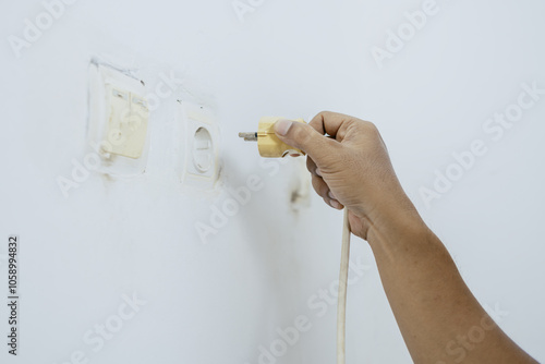 Male hand plugging charger cable into wall socket. Ready to connect, plug in electricity. photo