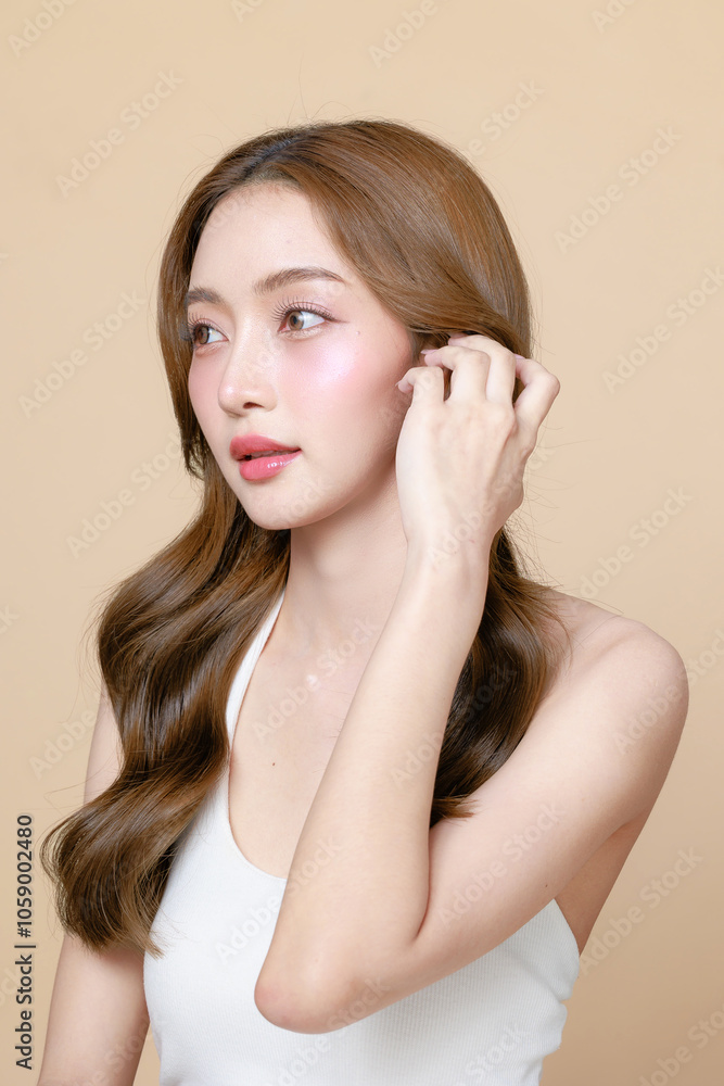 Young Asian beauty woman curly long hair with korean makeup style touch her face and perfect skin on isolated beige background. Facial treatment, Cosmetology, plastic surgery. Young Asian beauty woman curly long hair with korean makeup style touch her face and perfect skin on isolated beige background. Facial treatment, Cosmetology, plastic surgery.