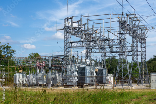 A wide-angle view of an electrical substation framed by a clear blue sky. photo