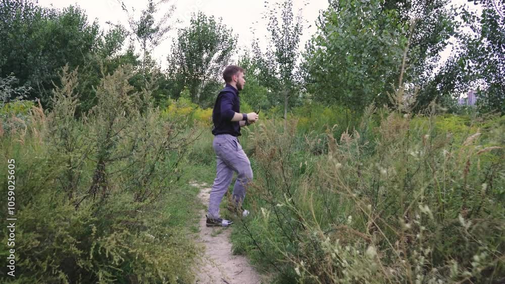 A young man wanders through a dense, green landscape in a dark shirt. Capturing a calm and peaceful moment in nature, ideal for concepts of solitude, mindfulness, and outdoor lifestyle. A young man wanders through a dense, green landscape in a dark shirt. Capturing a calm and peaceful moment in nature, ideal for concepts of solitude, mindfulness, and outdoor lifestyle.