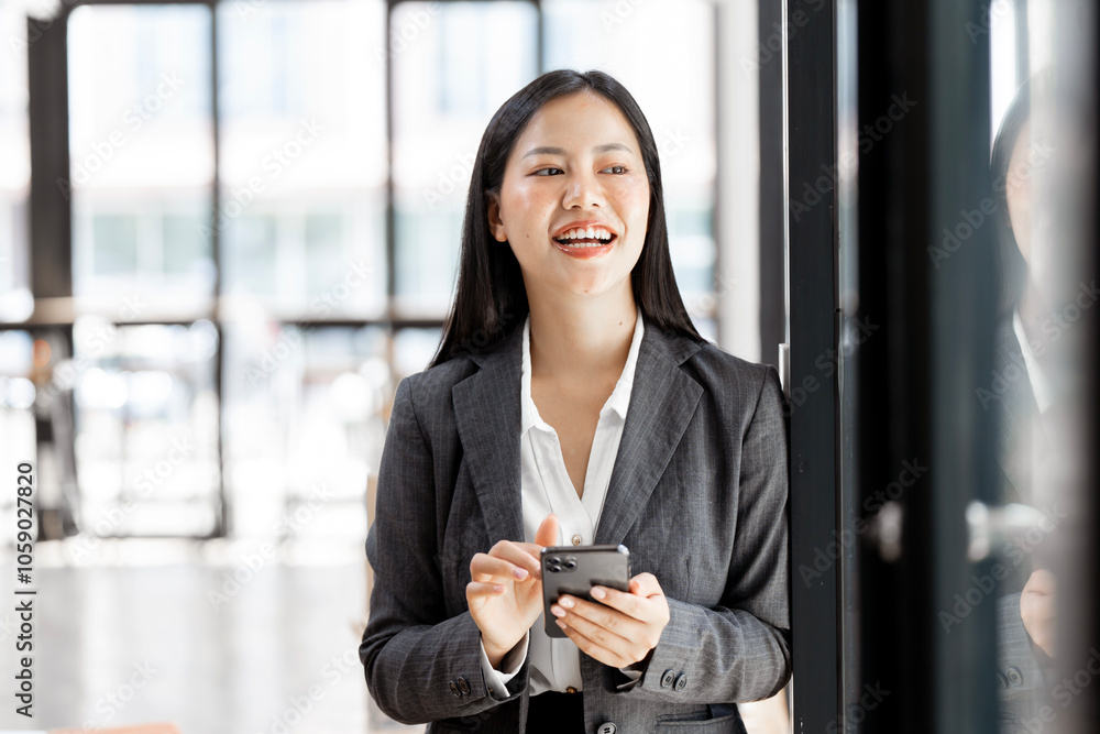 miling businesswoman using phone in office. Small business entrepreneur looking up and smiling. miling businesswoman using phone in office. Small business entrepreneur looking up and smiling.
