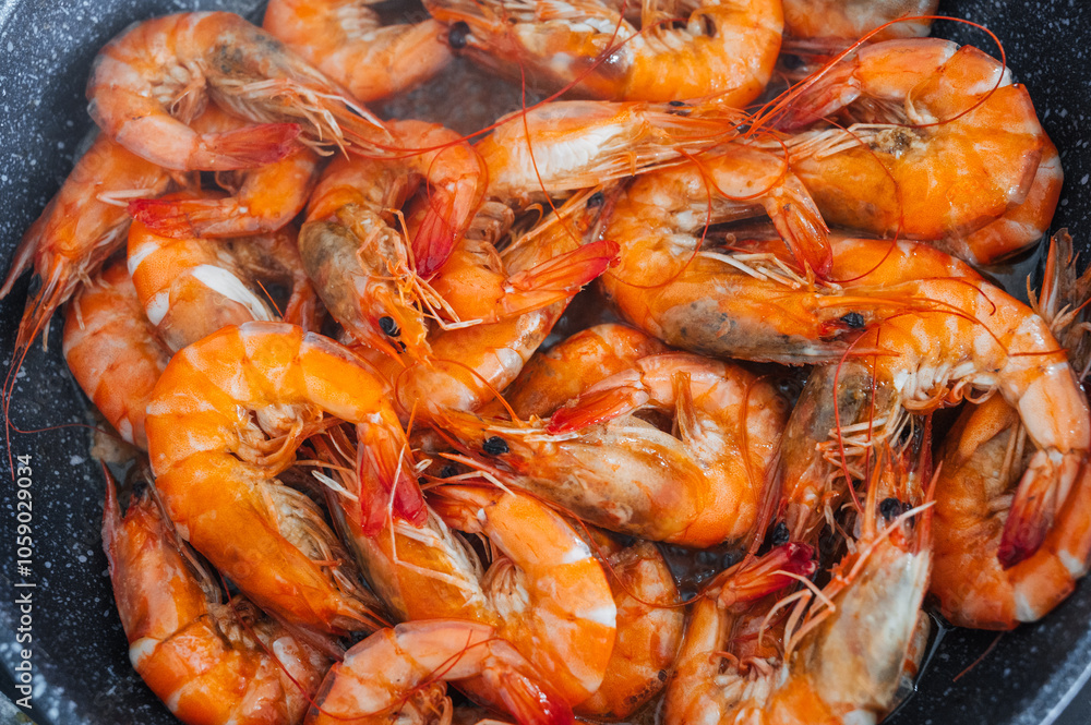 A close-up view of the shrimp fried in oil in a frying pan. A close-up view of the shrimp fried in oil in a frying pan.