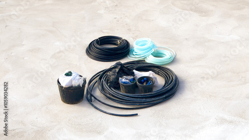 Assorted coils of cables and tubes with connectors arranged on a concrete surface.